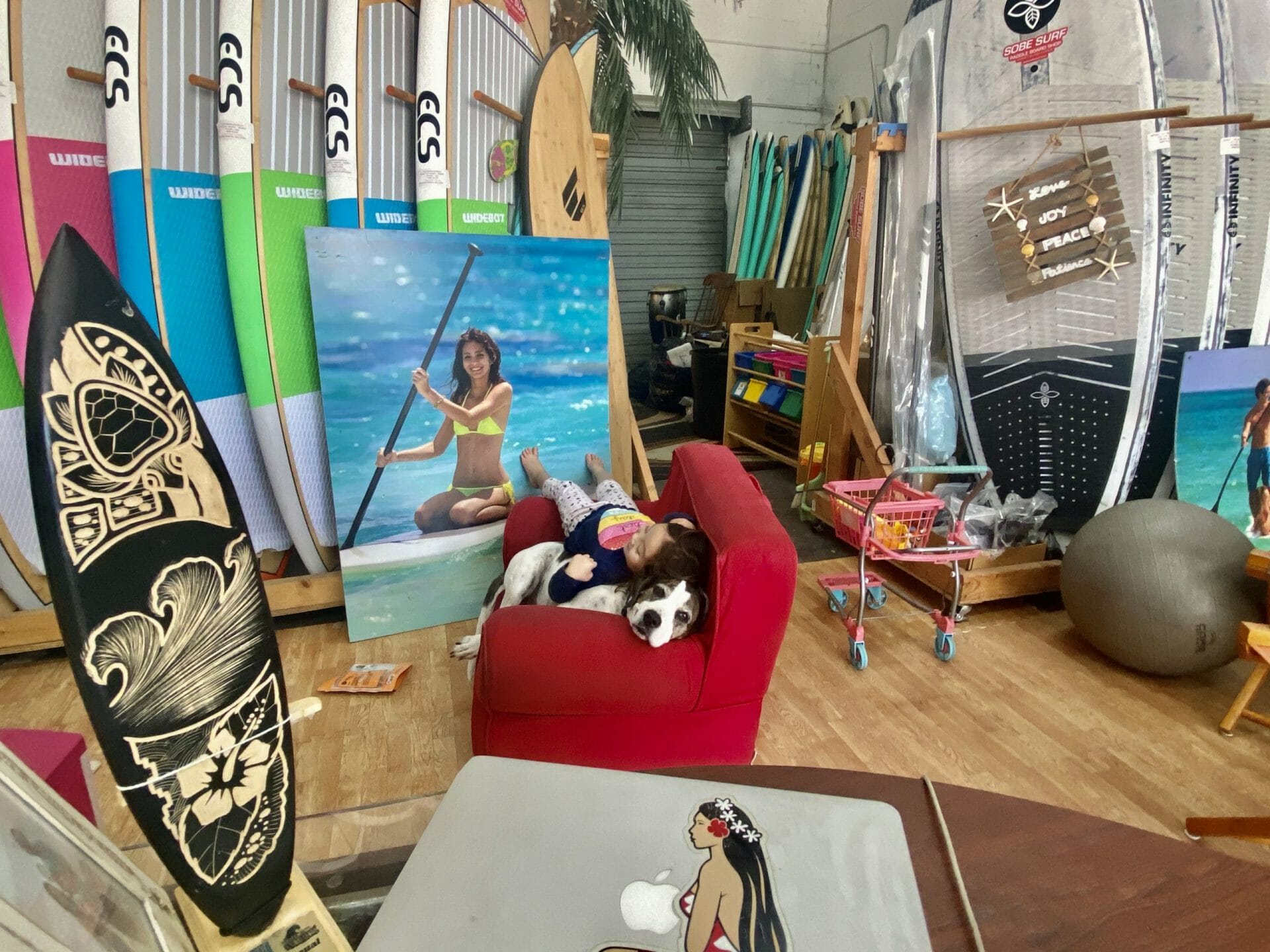 SOBE SURF & PADDLE SHOP PIC 3 AUDREY LAYING ON KONA SoBe Surf Paddle Board Shop Florida Cocoa Beach Merritt Island Miami Owner Girard Middleton with daughter Audrey